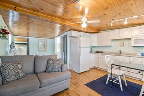 A modern kitchen with white cabinets, a refrigerator, a microwave, and a dining area with a glass table and white chairs. - Bayou Villa w/ Dock, Kayaks & Fire Pit Fun (Pensacola)