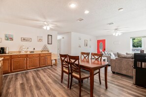 A spacious living area with a dining table, wooden cabinets, and a red accent wall. - Bayou Villa w/ Dock, Kayaks & Fire Pit Fun (Pensacola)