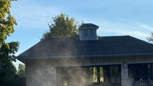 A stone building with a pool, a stone bench, and a chimney.