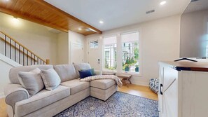 A living room with a sectional sofa, a coffee table, a patterned rug, a staircase, and a view of the outdoors. - Union Pier Stunner: Brand New with Pool Access (Union Pier)