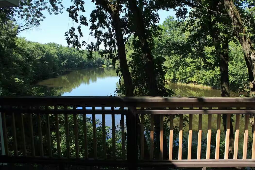 A wooden deck overlooking a calm lake surrounded by dense trees.