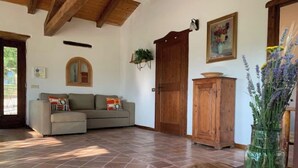 Un salon avec un canapé, un meuble en bois et un vase rempli de fleurs.