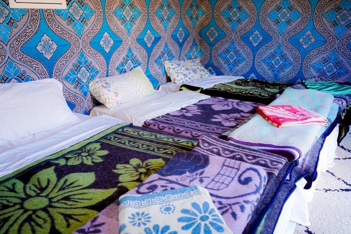 Quarto com duas camas, colchas estampadas e parede com design geométrico.