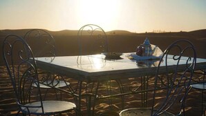 Una mesa con sillas en un paisaje desértico, con una vista despejada del horizonte.