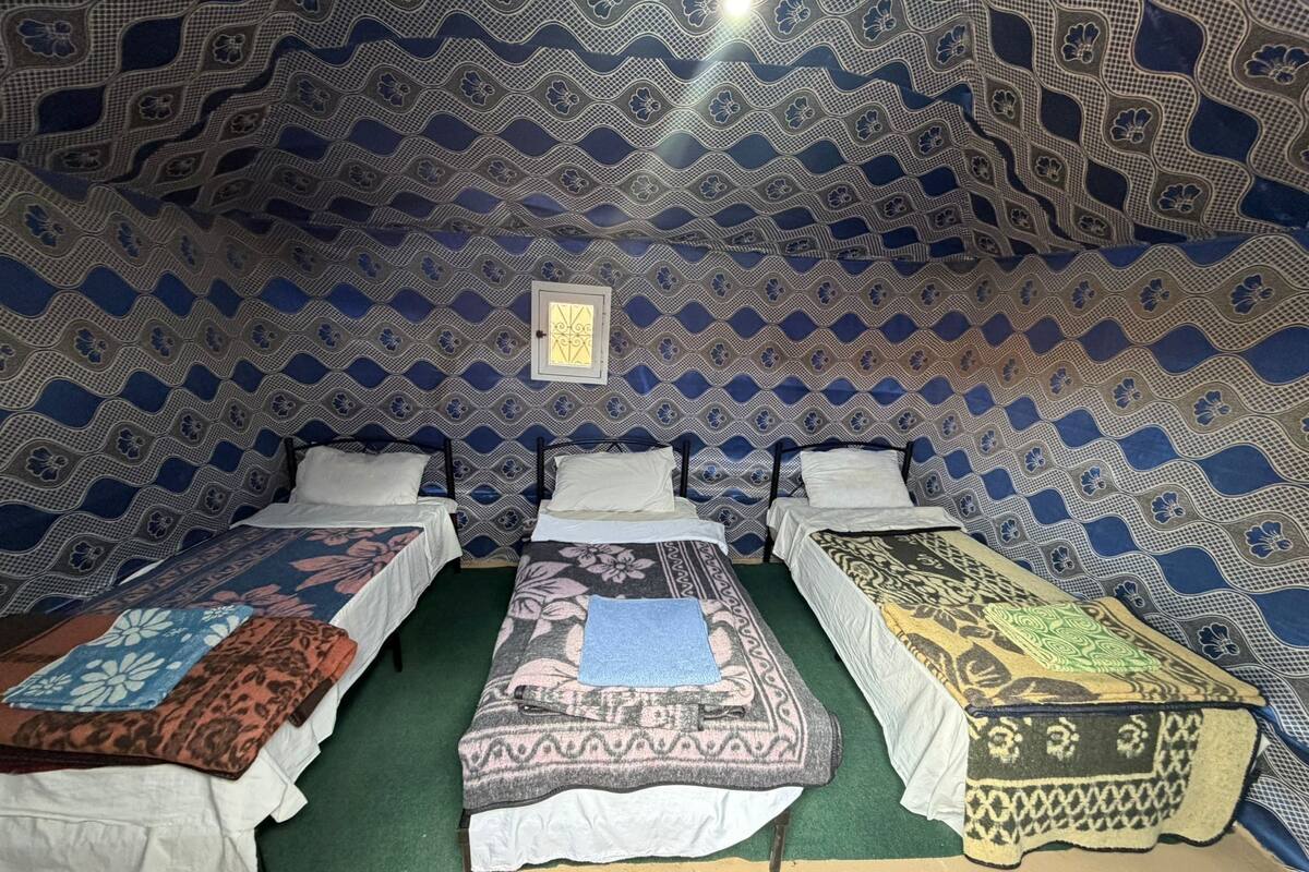 Quarto com três camas, cada uma com um colcha de padrão diferente.