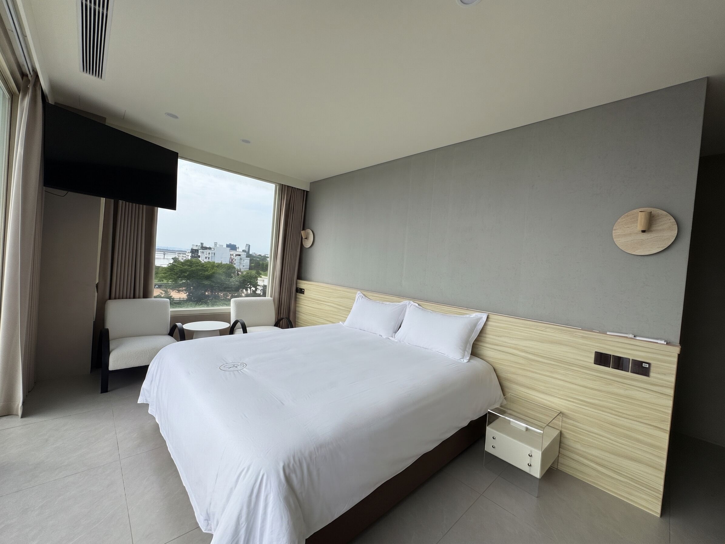 Una habitación de hotel moderna con una cama grande, un escritorio y vistas a la ciudad.