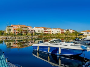Un puerto deportivo con un barco amarrado frente a una hilera de edificios de varios pisos con balcones.