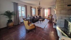A spacious living room with a large sectional sofa, a yellow armchair, a fireplace, and a large window.
