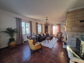 A spacious living room with a large sectional sofa, a yellow armchair, a fireplace, and a large window. - Villa Saint-Jacques on the heights of Bastia (Bastia)