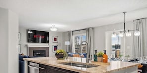 Una cocina moderna con horno empotrado, una isla grande con fregadero y un televisor de pantalla plana montado sobre el horno.
