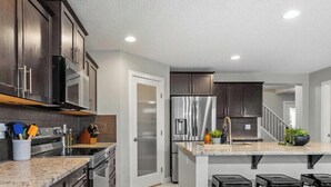 Une cuisine moderne avec des meubles de couleur sombre, des appareils électroménagers en acier inoxydable et un plan de travail en granit.