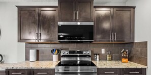 A kitchen with dark cabinets, a stainless steel range, and a granite countertop.