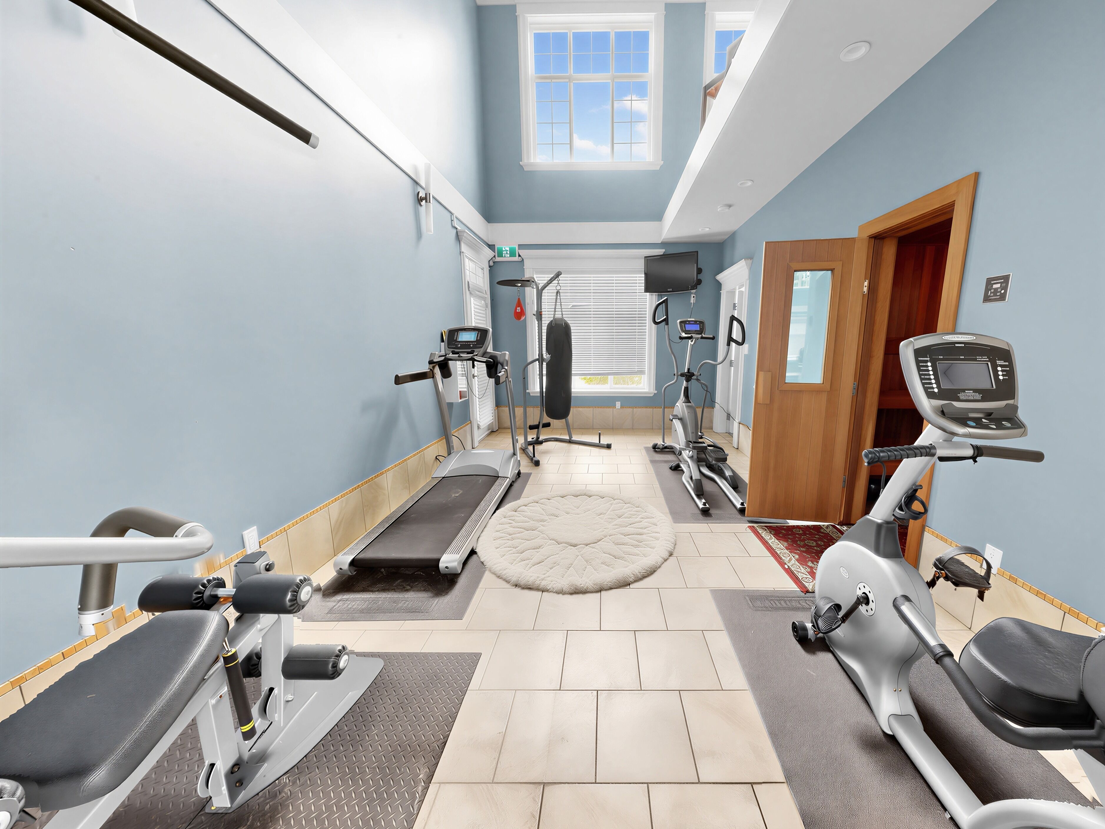 Une salle de sport équipée de tapis de course, de vélos elliptiques et de matériel de musculation.