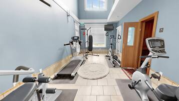 Une salle de sport équipée de tapis de course, de vélos elliptiques et de matériel de musculation.