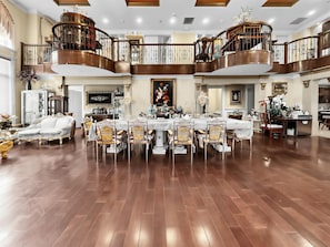 Un'ampia sala da pranzo con soffitto alto, ringhiere elaborate e un lampadario.