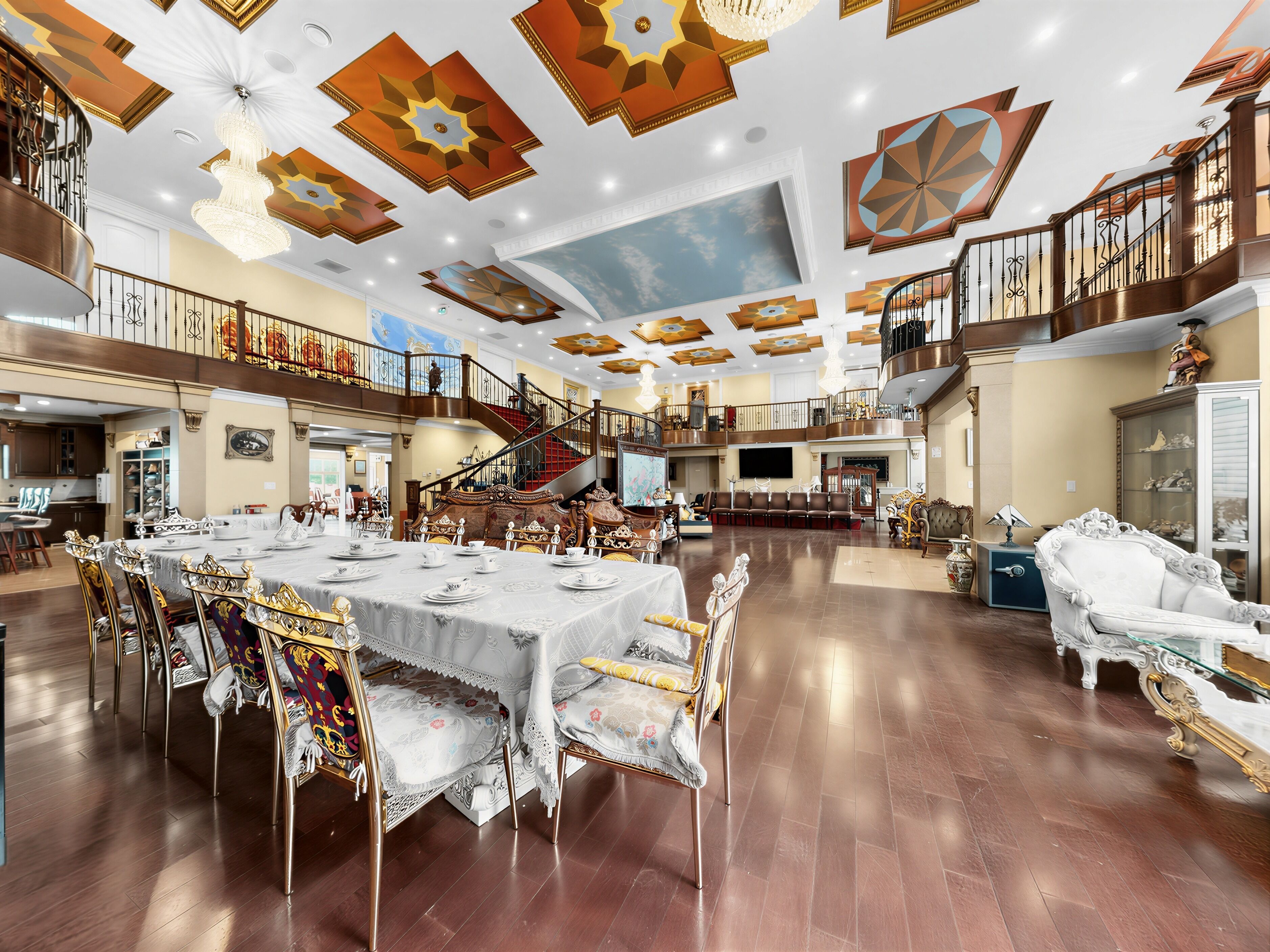 A spacious hotel lobby with a grand staircase, a dining area with ornate chairs, and a large chandelier.