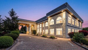 A large, multi-story building with a stone facade, arched windows, and a covered entrance.