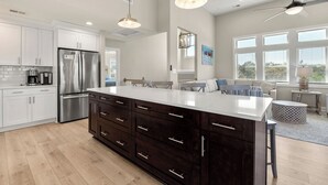 A modern kitchen with a large island, stainless steel appliances, and pendant lighting. - Saltwater Pool | Hot Tub | Rec Room | Dogs OK (Corolla)
