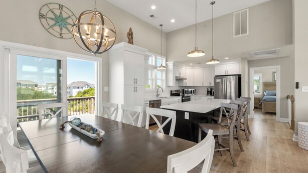 A modern kitchen with white cabinets, a large island, and pendant lighting. - Saltwater Pool | Hot Tub | Rec Room | Dogs OK (Corolla)