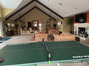 Ein großzügiger Innenbereich mit Tischtennisplatte, Korbmöbeln, Kamin und Essbereich.