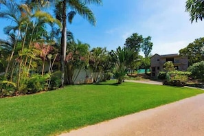 A residential area with a well-maintained lawn, palm trees, and a modern two-story house. - Hispaniola • Beach walk • Mega private pool • 3 BR (Sosúa)