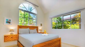 Un dormitorio con una cama grande, dos mesitas de noche y una ventana con vistas al verdor.