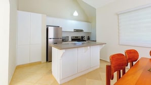 Una cocina moderna con armarios blancos, un refrigerador de acero inoxidable y una mesa de comedor de madera con sillas.