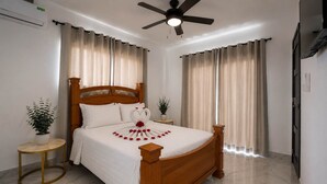 A bedroom with a wooden bed, two bedside tables, a ceiling fan, and curtains. - Sun-Filled Villa • Sunlit Pool • Just Finished (Sosúa)