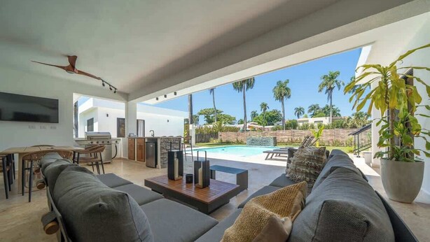 Una sala de estar moderna con vista a la piscina, un comedor y una cocina.