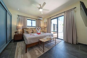A hotel room with a bed, a ceiling fan, a nightstand, a bench, and a view of the outside. - Elegance, Comfort, Location, 4BR Villa (Cabarete)