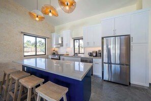 A modern kitchen with a central island, white cabinets, stainless steel appliances, and a large window. - Elegance, Comfort, Location, 4BR Villa (Cabarete)