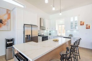 Una cocina moderna con una isla grande, electrodomésticos de acero inoxidable y taburetes de bar.