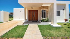 Une maison moderne avec une façade en pierre, une porte en bois et un chemin en pierre menant à l’entrée.
