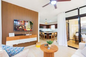 A modern living room with a flat-screen TV, wooden paneling, a round coffee table, and a dining area with chairs. - Modern • Private • Relax (Sosúa)