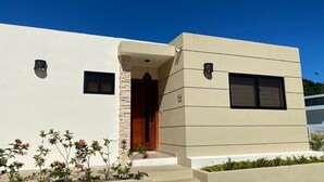 Un bâtiment moderne avec une façade beige, une porte en bois et une petite fenêtre.