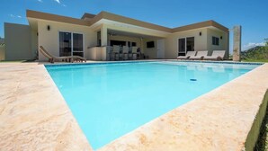 Una casa moderna con piscina, un porche cubierto y un cielo azul despejado.