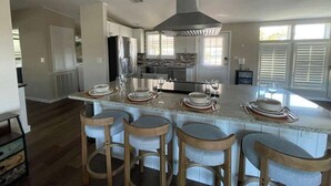 A modern kitchen with a central island, bar stools, and a large range hood. - Perfect Home in St. James City (Saint James City)