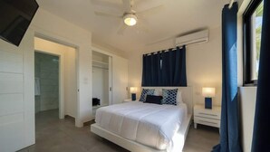 A bedroom with a bed, bedside tables, a ceiling fan, and a window with curtains. - Location • Vibe • Style (Sosúa)