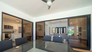 A modern kitchen with a microwave, stove, and dining area with a glass table and chairs. - Location • Vibe • Style (Sosúa)