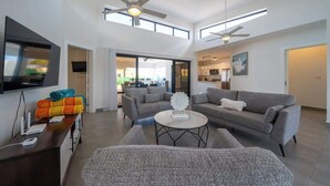 A spacious living area with a sofa set, a coffee table, and a TV mounted on the wall. - Location • Vibe • Style (Sosúa)