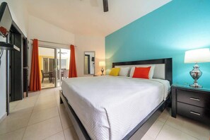 Ein Hotelzimmer mit Bett, Nachttisch, Lampe und Blick ins Freie.