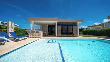 A modern pool area with lounge chairs and a building with large windows.