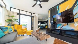A modern living room with a sofa, yellow chairs, a coffee table, and a TV. - Modern 2BR Villa · Private Pool · Casa Linda (Sosúa)