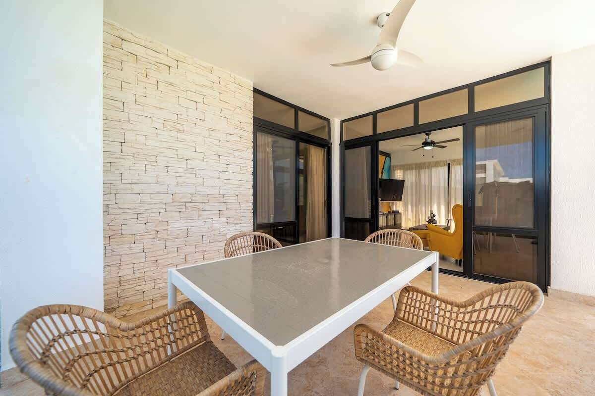 A dining area with a table and chairs, a ceiling fan, and a brick wall.