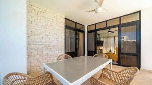 A dining area with a table and chairs, a ceiling fan, and a brick wall. - Modern 2BR Villa · Private Pool · Casa Linda (Sosúa)