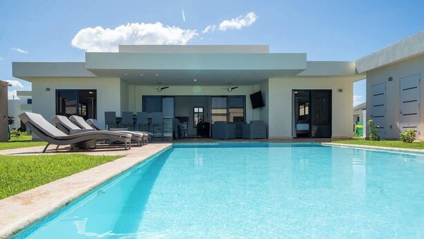 Ein modernes Gebäude mit Schwimmbad, Liegestühlen und einer überdachten Terrasse.