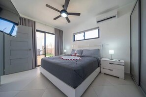 Ein modernes Schlafzimmer mit Bett, Nachttisch, Deckenventilator und Fenster.