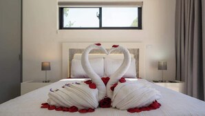 Ein Bett mit einer herzförmigen Handtuchgestaltung und Rosenblättern.