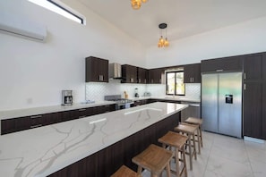 A modern kitchen with a large island, dark cabinetry, and stainless steel appliances. - New • All King • A/C in Living Room • Privacy (Sosúa)