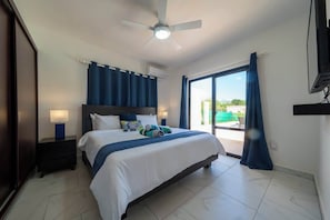A hotel room with a bed, a ceiling fan, a TV, and a view through a glass door. - New • All King • A/C in Living Room • Privacy (Sosúa)